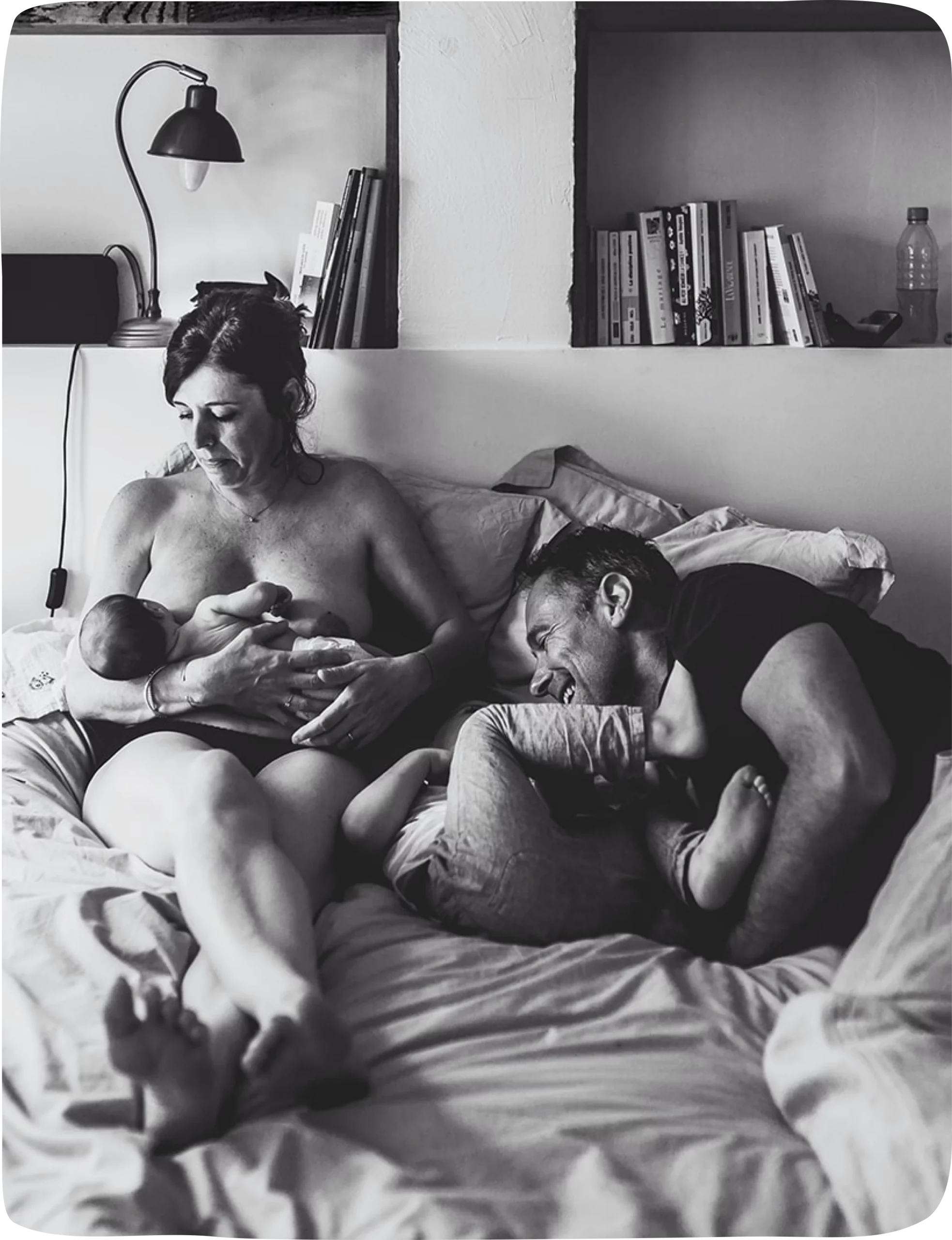 Photo de famille : maman allaite bébé et papa joue avec le frère. Par Marina Contis.